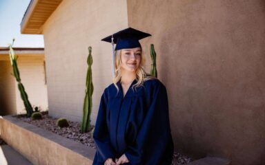 Brianna, una graduada de 16 años de la Academia Virtual de Arizona, sonríe con su toga y birrete.