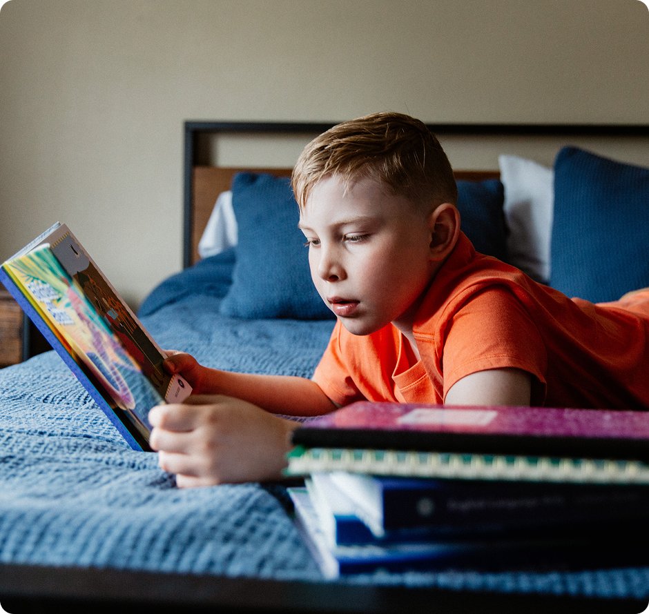 Estudiante de primaria leyendo un libro en su cama